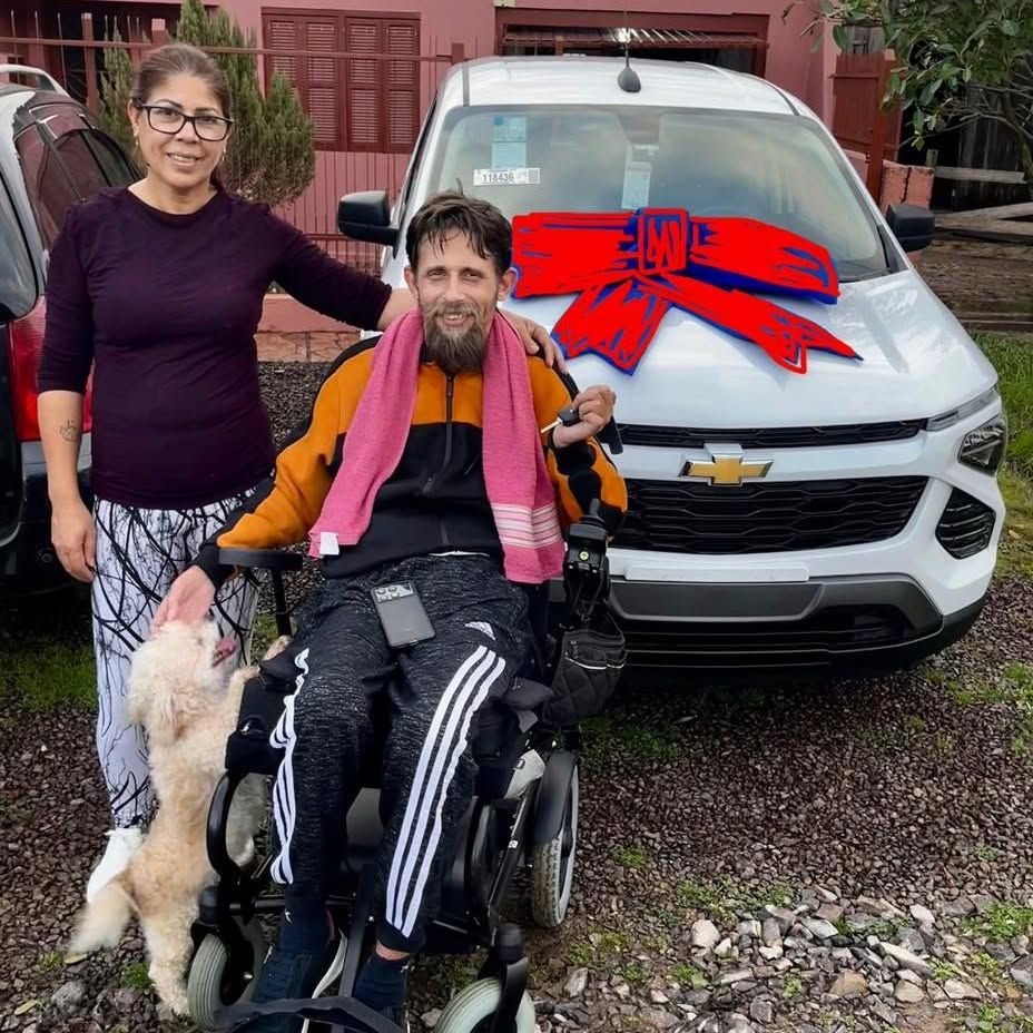 Cliente em cadeira de rodas com a família e o cachorro, em frente ao Chevrolet novo