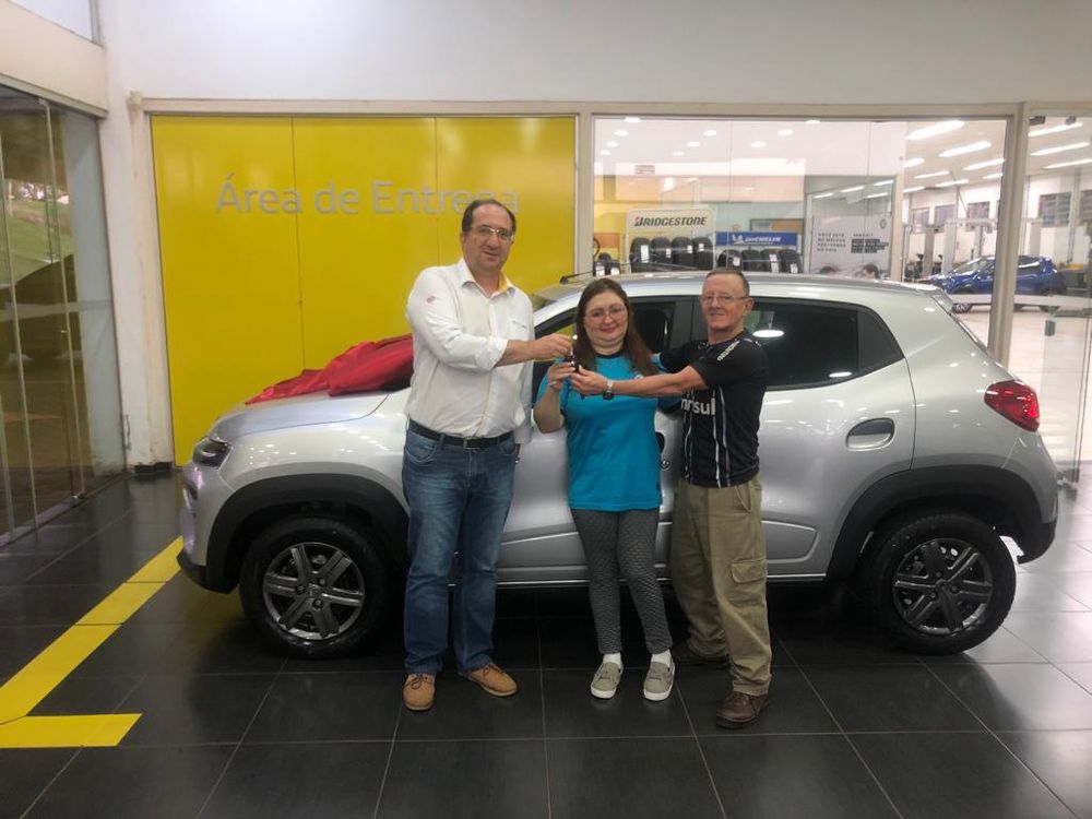 Cliente recebendo a chave do Renault Kwid na área de entrega